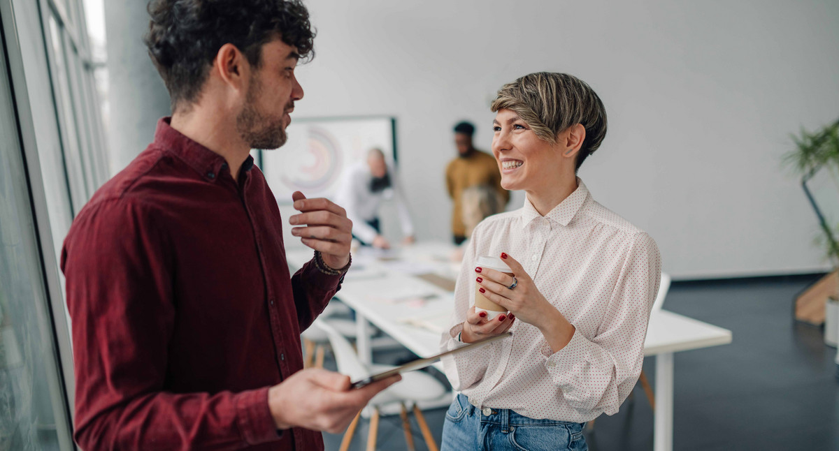 Zwei Kollegen unterhalten sich in einem modernen Büro.