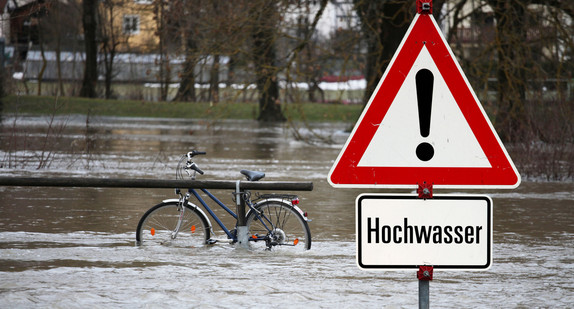 Überflutete Straße mit einem Fahrrad in der Mitte. 