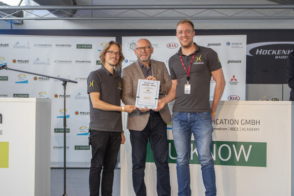 Verkehrsminister Winfried Hermann MdL bei der Übergabe der Urkunde an Marvin Panek und Maximilian Camp von Steereon, einem der zwölf Finalisten des Start-up Awards 2019 im Rahmen des e4 TESTIVAL (Bilderquelle: Kira Chaparro_© emodrom) 