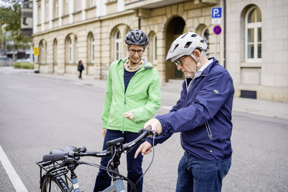 Verkehrsminister Winfried Hermann und Staatssekretärin Elke Zimmer, beide mit Fahrradhelm, stehen neben einem Fahrrad und begutachten es.h.