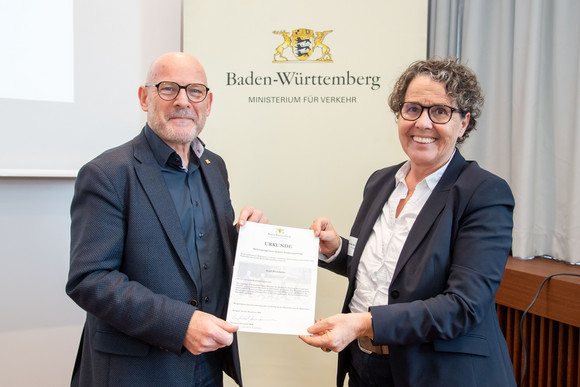 Fussverkehr 1.000 Zebrastreifen für Baden-Württemberg Winfried Hermann überreicht die Urkunde der Bürgermeisterin für Planen, Bauen, Umwelt und Kunst Sibylle Schüssler der Stadt Pforzheim.