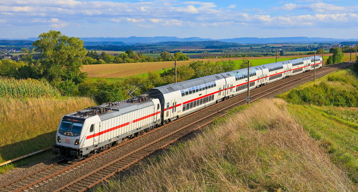 Ein Intercity-Zug fährt durch eine grüne Landschaft.