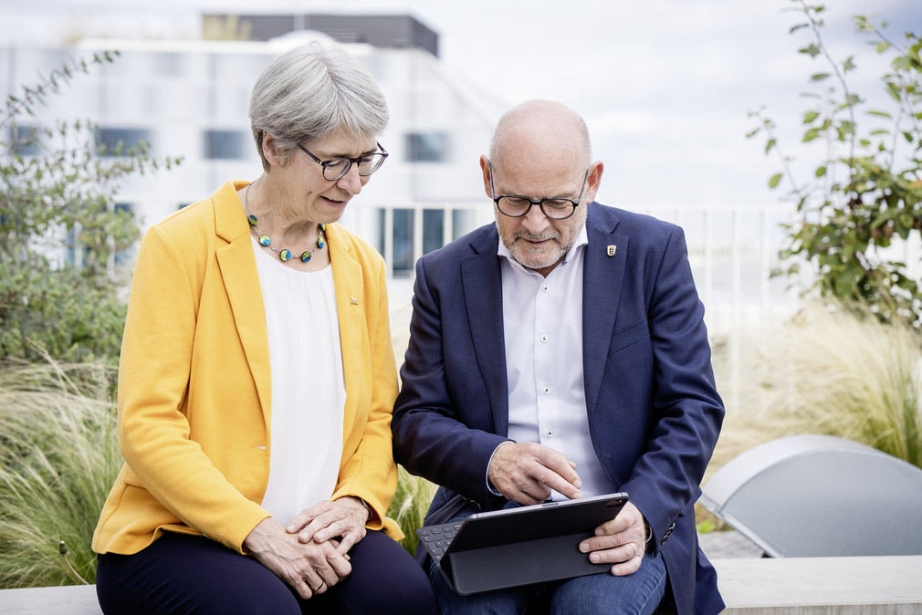 Verkehrsminister Winfried Hermann und Staatssekretärin Elke Zimmer, wie sie etwas auf dem Tablet anschauen.