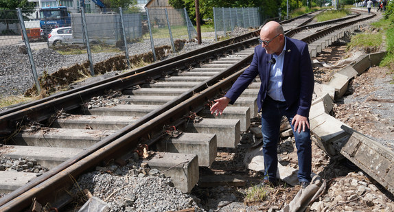 Minister Hermann steht vor einem Gleis, das vom Unwetter zerstört wurde.