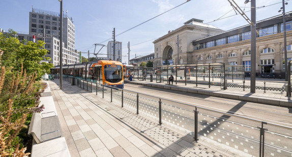 Eine Straßenbahn fährt vor einem Bahnhof.