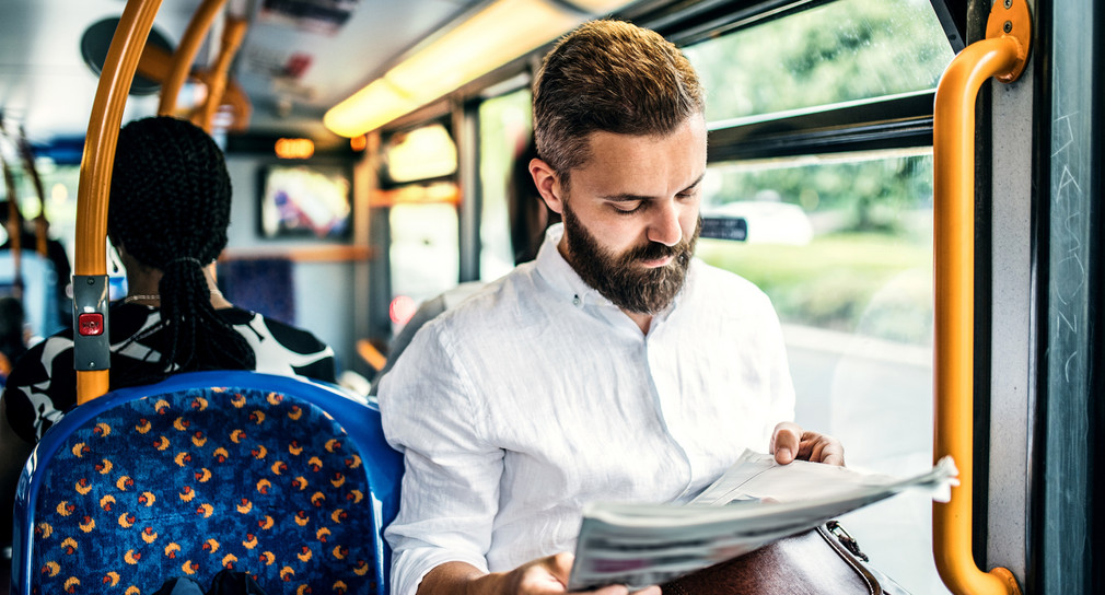 Ein Mann fährt mit dem Bus und liest Zeitung (Bild: Fotolia.com/226462799)