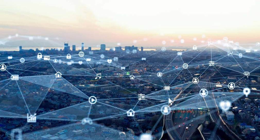 Stadt aus der Luftperspektive über die ein virtuelles Netzwerk gelegt wurde, das zeigt, wie verschiedene Personen und Orte über Daten miteinander verknüpft werden.