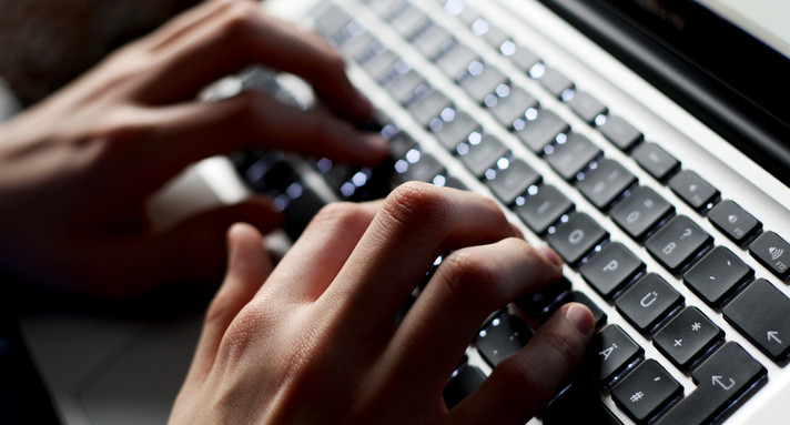 Hände, die auf einer Laptop-Tastatur tippen