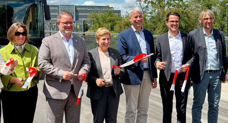 Eine Gruppe aus verschiedenen Politikerinnen und Politikern schneiden auf einer Brücke ein Band durch.