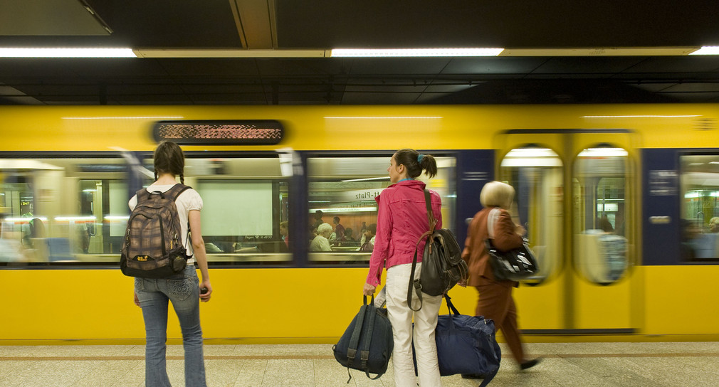 Stuttgarter U-Bahn fährt an einem unterirdischen Bahnsteig ein auf dem Fahrgäste warten.