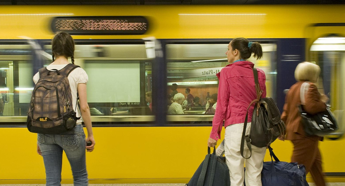 Stuttgarter U-Bahn fährt an einem unterirdischen Bahnsteig ein auf dem Fahrgäste warten.