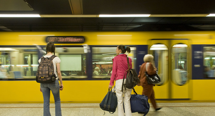 Stuttgarter U-Bahn fährt an einem unterirdischen Bahnsteig ein auf dem Fahrgäste warten.