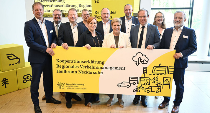 Eine Gruppe von Politikerinnen und Politikern steht zu einem Gruppenfoto zusammen. Sie halten gemeinsam ein Schild mit der Überschrift Kooperationserklärung Regionales Verkehrsmanagement Heilbronn Neckarsulm in der Hand.