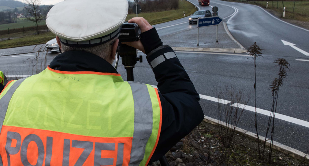 Ein Polizist kontrolliert am Ende der Autobahn A81 mit einem Lasermessgerät die Geschwindigkeit der Fahrzeuge.