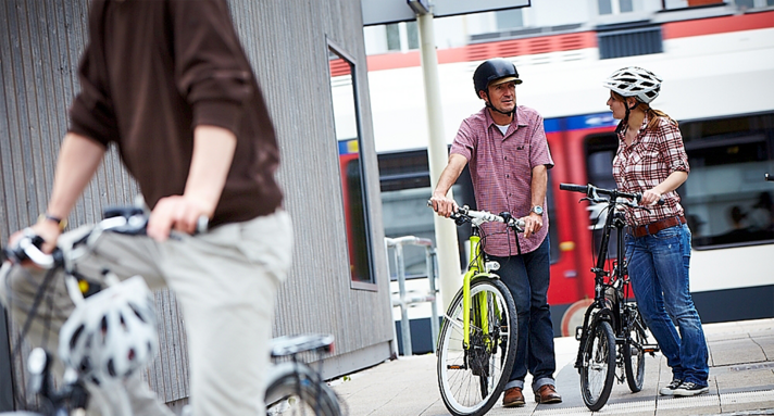 Fahrradfahrer die vor einer Bahn stehen.