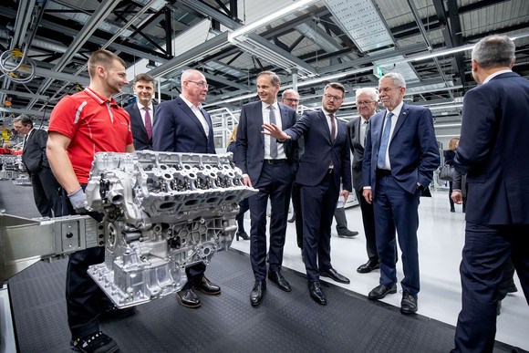 Besuch Österreichischer Bundespräsident besucht Baden-Württemberg Stellvertretender Aufsichtsratsvorsitzender der Porsche AG Uwe Hück (3.v.l.), Vorstandsvorsitzender der Porsche AG Oliver Blume (4.v.l.), Ministerpräsident Winfried Kretschmann (3.v.r.) und österreichischer Bundespräsident Dr. Alexander Van der Bellen (2.v.r.) betrachten einen Motorblock. (Bild: Staatsministerium Baden-Württemberg)