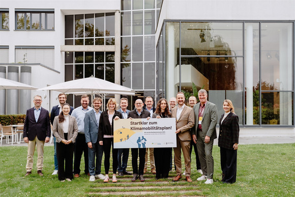 Die am Startklar-Programm für Klimamobilitätspläne teilnehmenden kommunalen Vertreterinnen und Vertreter gemeinsam mit Verkehrsminister Winfried Hermann und den Klimamobilitätsplan.Lotsinnen und -Lotsen vom Kompetenznetz Klima Mobil. Gemeinsam halten sie ein Schild mit der Aufschrift „Startklar zum Klimamobilitätsplan! Wir sind die Startklar-Kommunen 2025“.