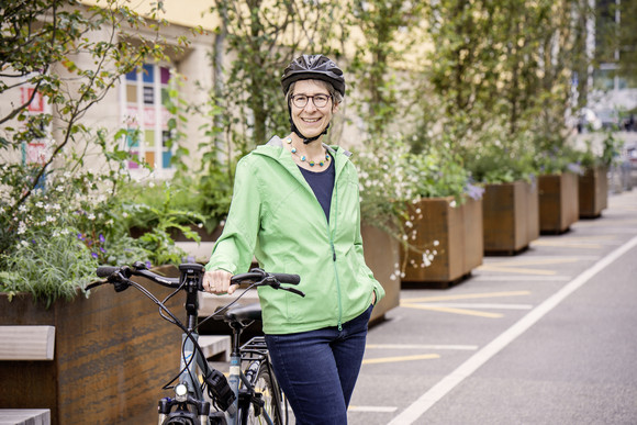 Staatssekretärin Elke Zimmer trägt einen Fahrradhelm und steht neben ihrem Fahrrad.