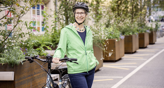 Staatssekretärin Elke Zimmer trägt einen Fahrradhelm und steht neben ihrem Fahrrad.