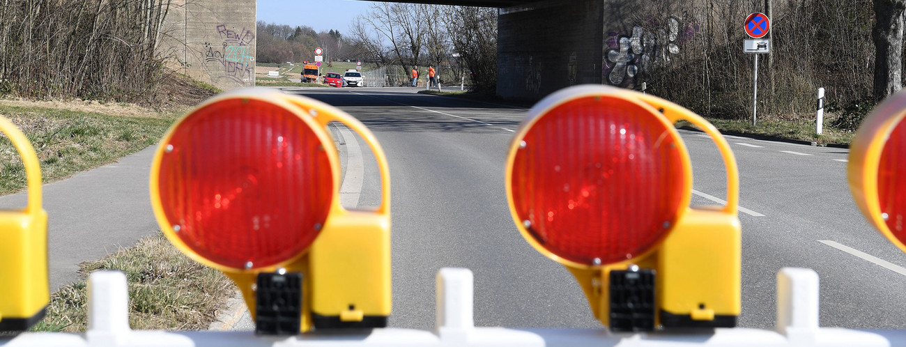 Absperrung auf einer Straße. Im Hintergrund eine Autobrücke.