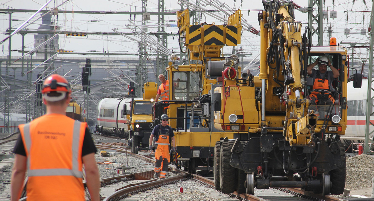 Gleisbauarbeiter und mehrere Bagger auf einer Baustelle im Gleisbett.