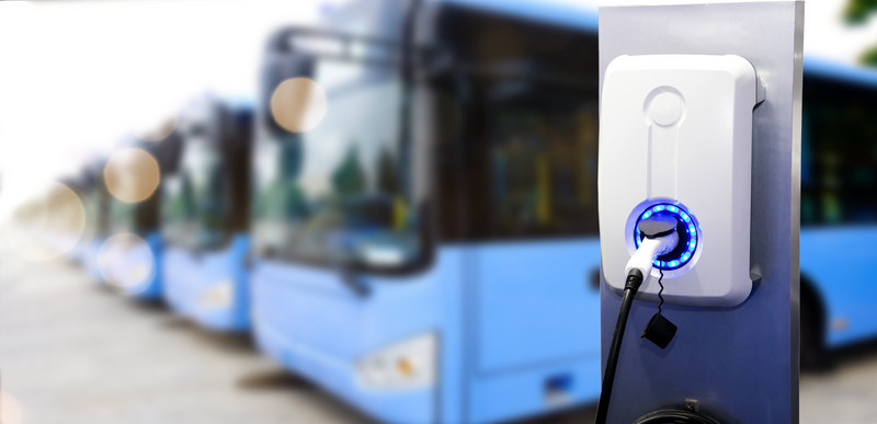 Busse laden an einer Ladesäule.