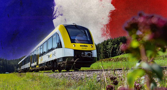 Zug auf Gleisen mit Frankreich-Flagge im Hintergrund.