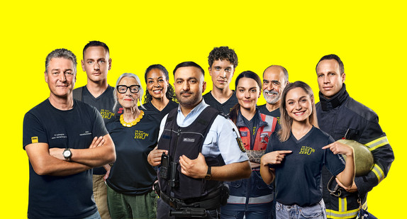 Ein Gruppenbild des Team Vison Zero. Bürger:innen, Feuerwehrleute, ein Polizist und ein Fahrsicherheitstrainer stehen nebeneinander.