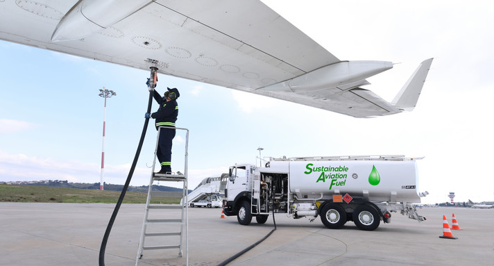 Ein Flugzeug wird von einem Techniker mit Sustainable Aviation Fluel aus einem Tanklaster betankt.