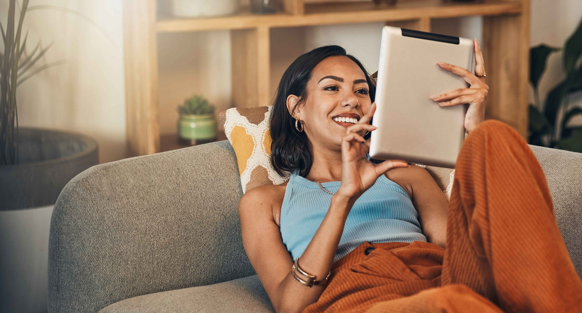 Frau entspannt sich auf der Couch mit Tablet.