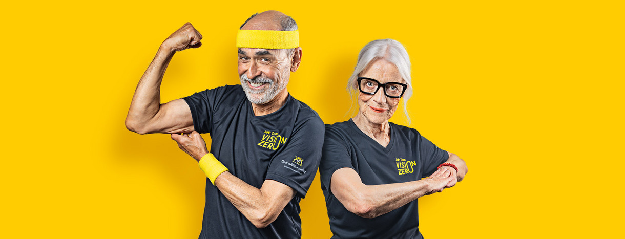 Ein Senior und eine Seniorin posieren sportlich vor einem gelben Hintergrund