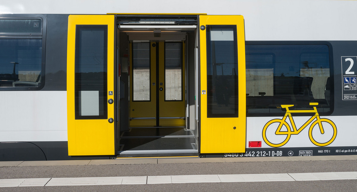 Ein weiß-gelber bwegt-Zug steht mit offener Türe an einem Bahnsteig.