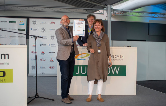 Verkehrsminister Winfried Hermann MdL mit Ursula Kloé (und im Hintergrund Jürgen Häussler, beide) / JU-KNOW bei der Preisübergabe an H2range, die nur über Video zugeschaltet waren. H2range ist einer der drei Gewinner des Start-up Awards 2019 im Rahmen des e4 TESTIVAL (Bilderquelle: Kira Chaparro_© emodrom)