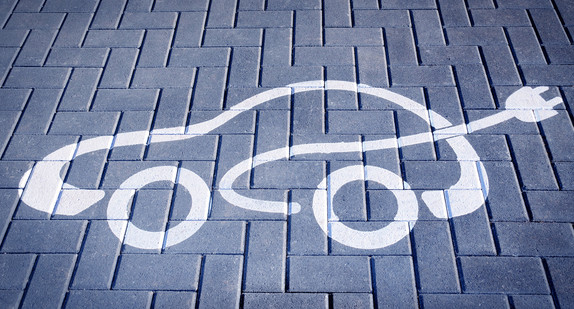 Auf den Boden eines Parkplatzes ist als Symbol ein Auto mit einem Stromladestecker aufgemalt.