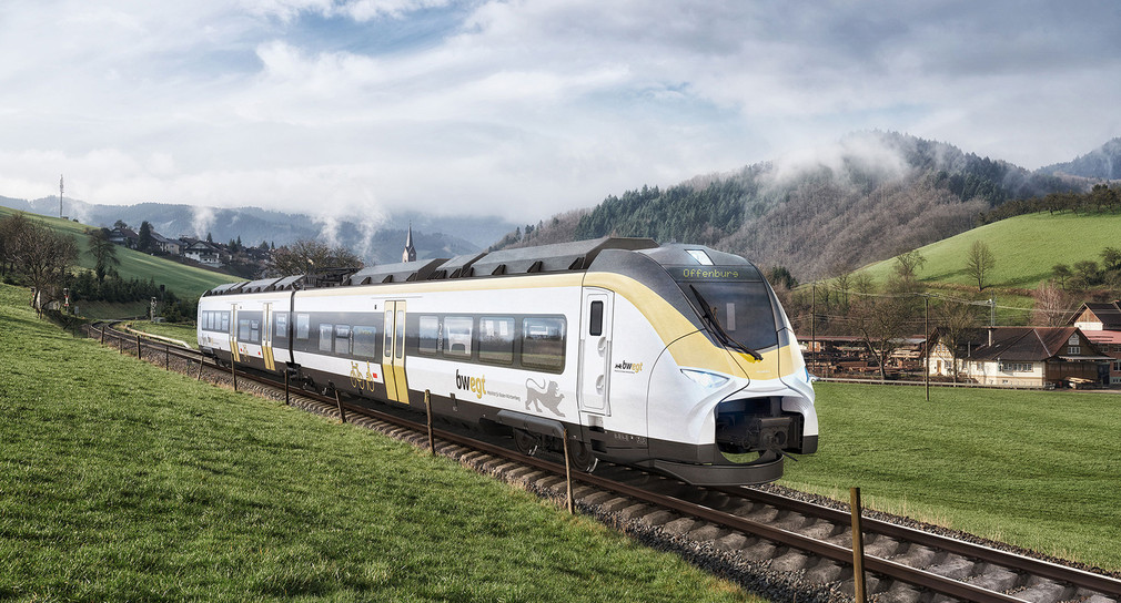 Ein weiß gelber Zug fährt auf Schienen durch eine grüne Landschaft.