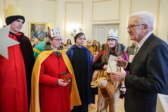 Aktion Dreikönigssingen Kretschmann empfängt Sternsingergruppen Ministerpräsident Winfried Kretschmann (rechts) überreicht Sternsingerinnen und Sternsingern einen Umschlag.