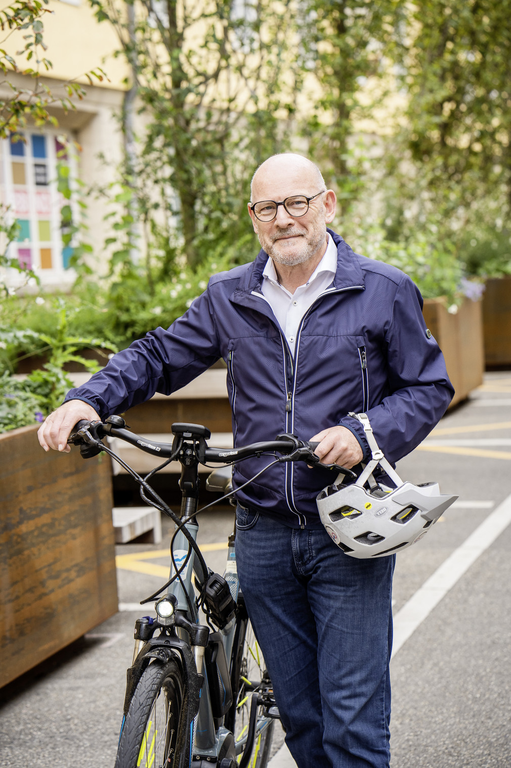 Verkehrsminister Winfried Hermann schiebt sein Fahrrad, ein Fahrradhelm hängt am Arm.