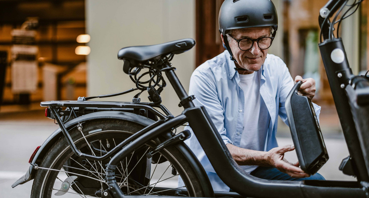 Älterer Mann tauscht den Akku eines E-Bikes.