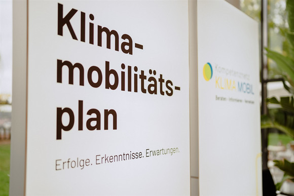 Der Titel der Veranstaltung „Klimamobilitätsplan: Erfolge. Erkenntnisse. Erwartungen“ auf einer leuchtenden Stellwand