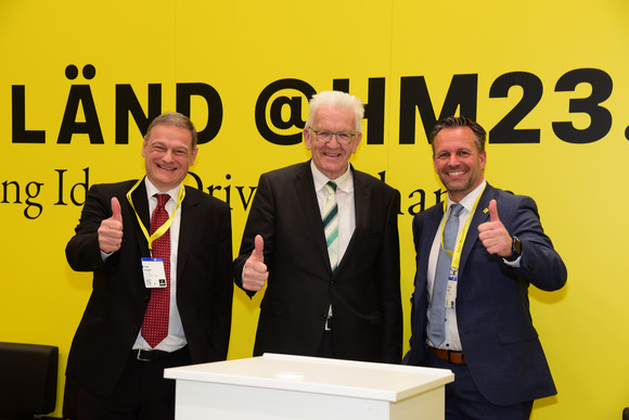 Industrie Kretschmann besucht Hannover Messe Franz Loogen, Geschäftsführer e-mobil BW GmbH (l.), Ministerpräsident Winfried Kretschmann (M.) und Dr. Christian Herzog, Geschäftsführer Baden-Württemberg International BW_i (r.), am Baden-Württemberg Pavillon „Energy Solutions"