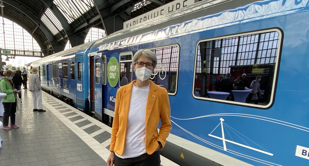 Staatssekretärin Zimmer steht vor dem blauen Zug am Karlsruher Hbf