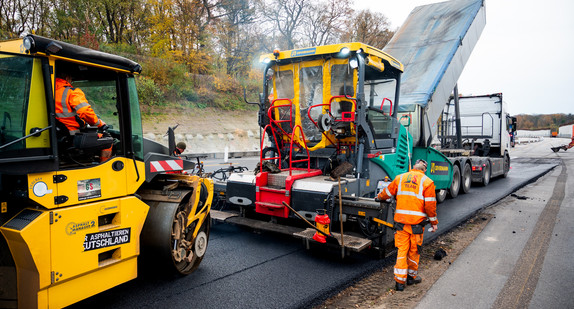 Ein Maschine asphaltiert eine Straße.
