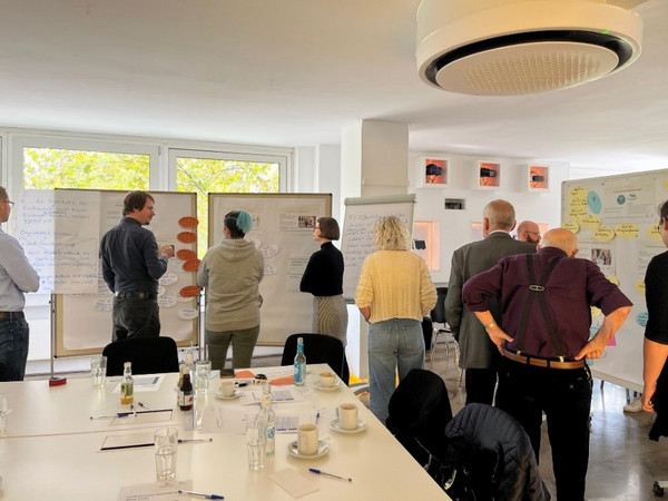 Bürgerinnen und Bürger kommen in Stuttgart miteinander ins Gespräch: Menschen informieren sich an Pinnwänden und diskutieren über die Inhalte