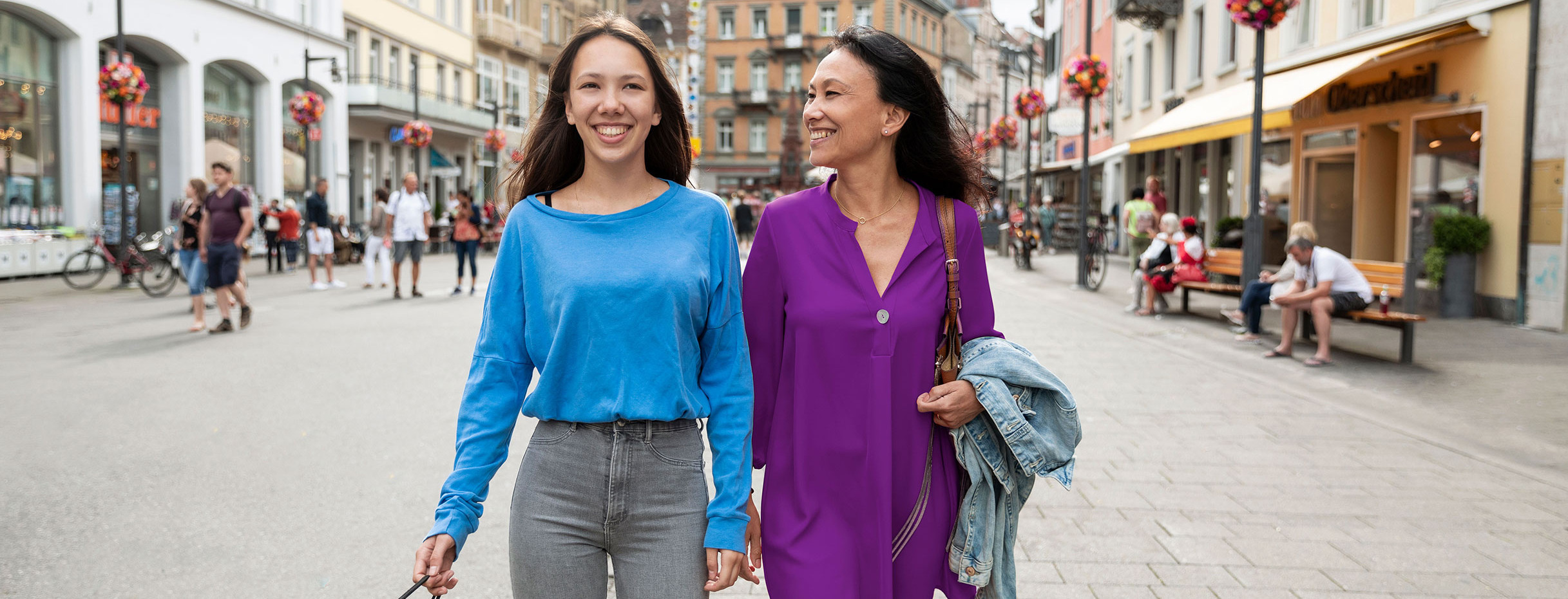 Zwei Frauen spazieren in einer Fußgängerzone.