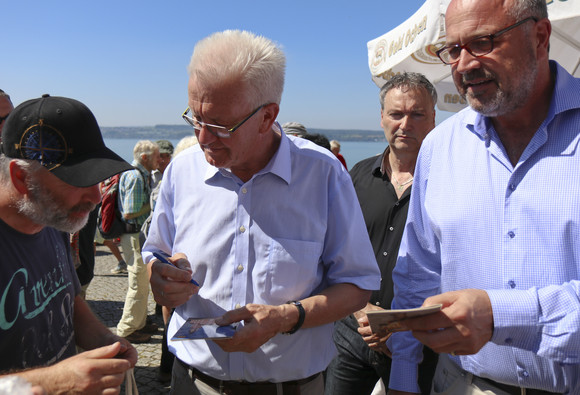 Sommertour Kretschmann wandert mit Bürgerinnen und Bürgern Ministerpräsident Winfried Kretschmann gibt einem Bürger ein Autogramm.