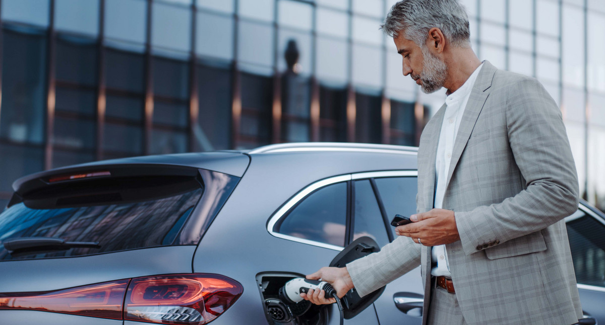 Mann hält Stromkabel an Ladestation für Elektrofahrzeuge, Nahaufnahme