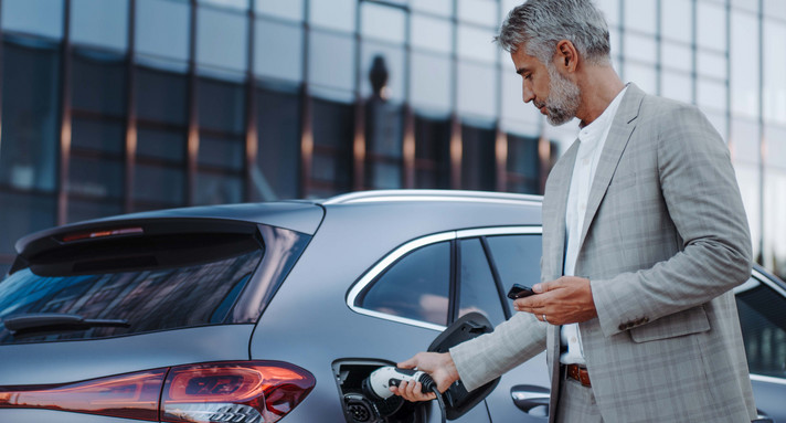Mann hält Stromkabel an Ladestation für Elektrofahrzeuge, Nahaufnahme