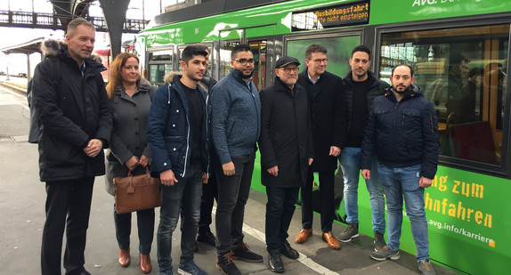 Minister Hermann mit Geflüchteten vor Zug 