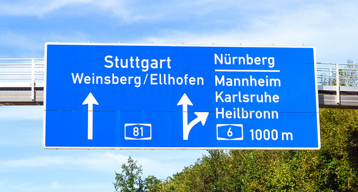 Ein großes Autobahnschild zeigt die Fahrrichtung an.