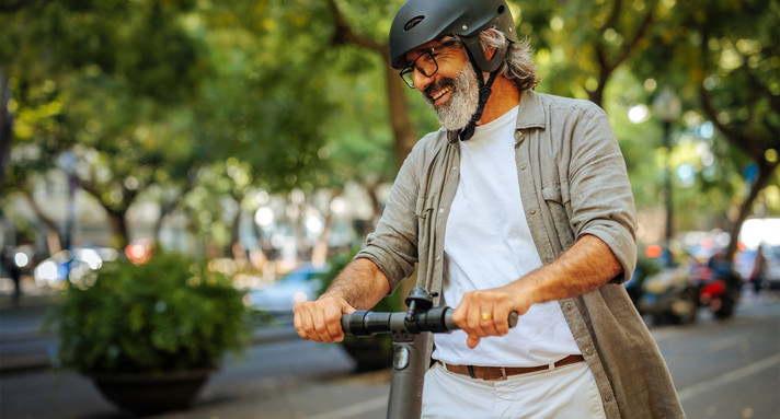 Fröhlicher reifer Mann auf Elektroroller.
